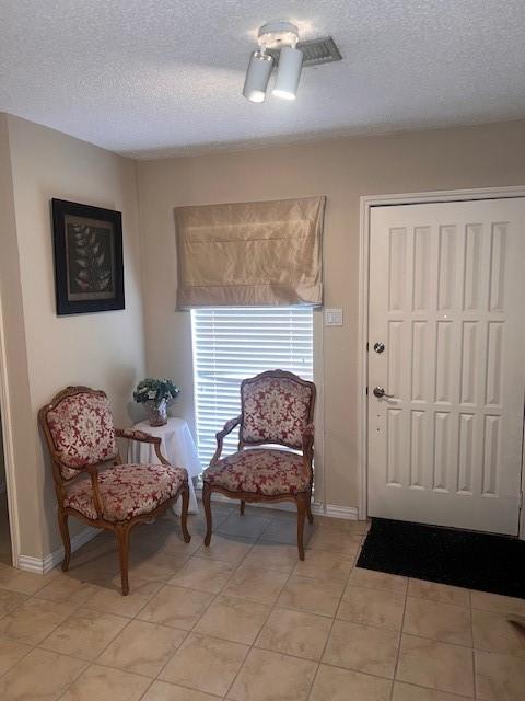 sitting room with a textured ceiling, baseboards, and light tile patterned floors