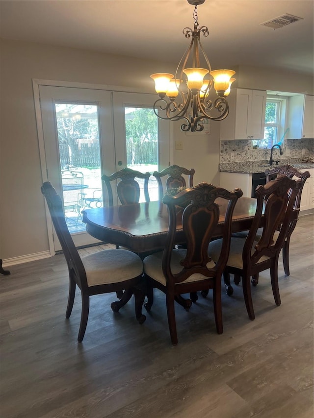 dining area with baseboards, light wood-type flooring, visible vents, and a notable chandelier