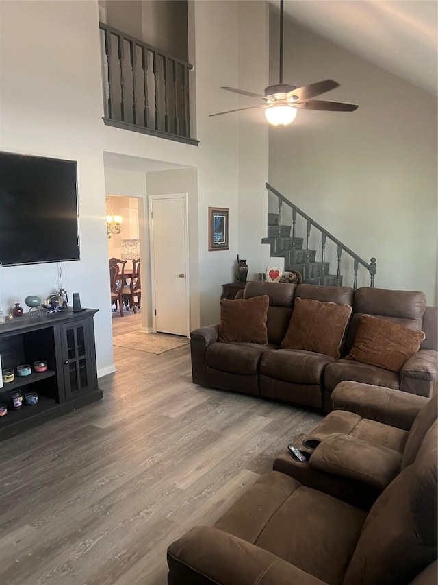 living area with ceiling fan, stairs, high vaulted ceiling, and wood finished floors