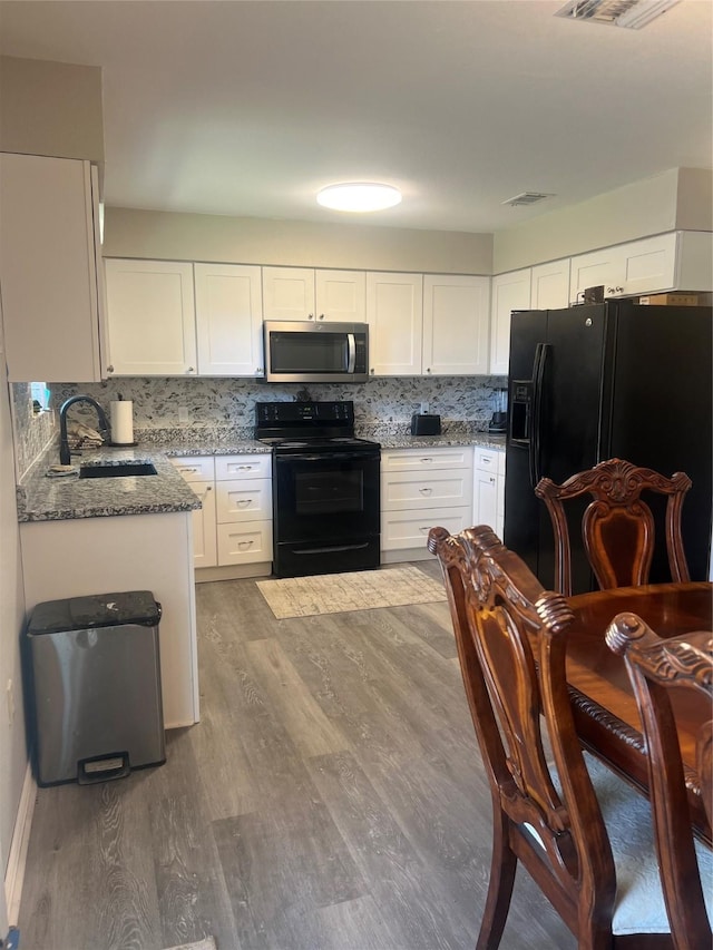 kitchen featuring tasteful backsplash, dark stone counters, a sink, and black appliances