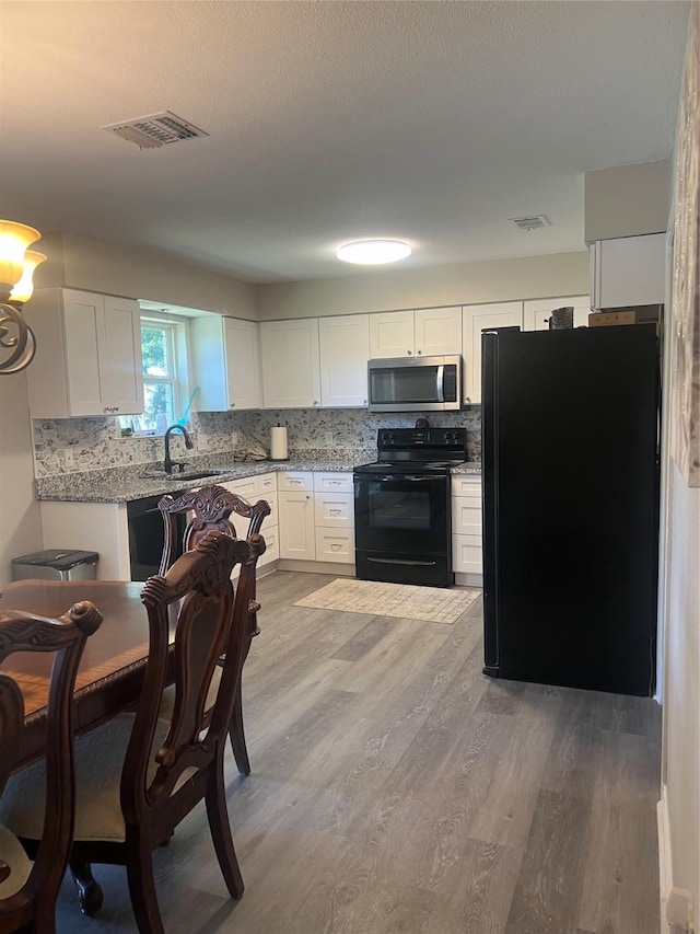 kitchen with visible vents, white cabinets, backsplash, black appliances, and a sink