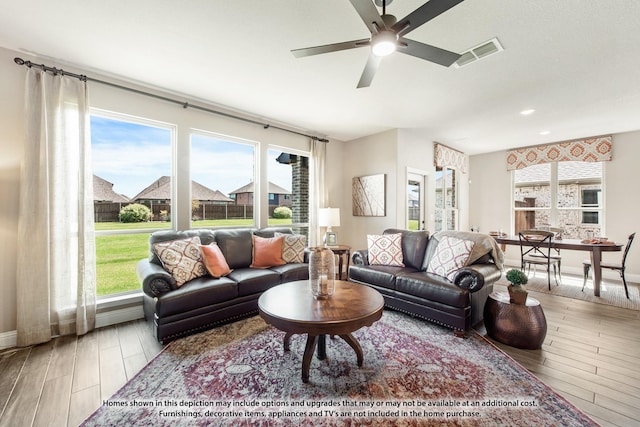 living area featuring ceiling fan, wood finished floors, visible vents, and baseboards