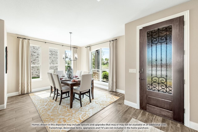 dining space featuring baseboards, an inviting chandelier, and wood finished floors