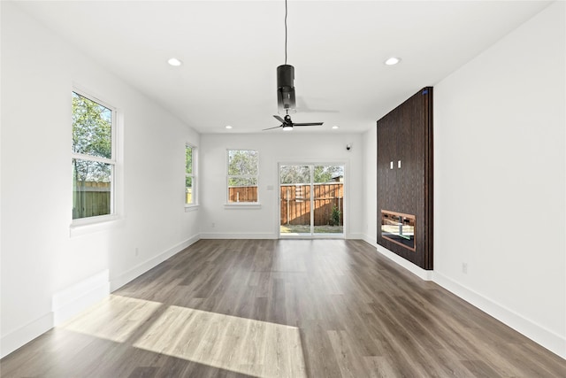 unfurnished living room featuring recessed lighting, wood finished floors, and a glass covered fireplace