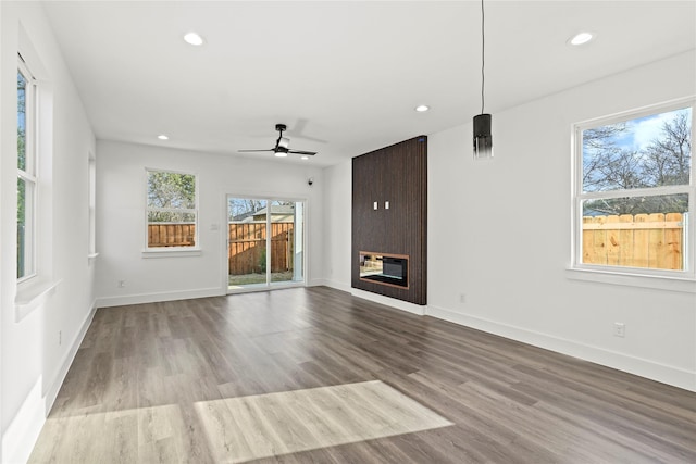 unfurnished living room with a fireplace, recessed lighting, ceiling fan, wood finished floors, and baseboards