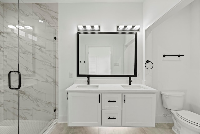 bathroom with a marble finish shower, double vanity, a sink, and toilet