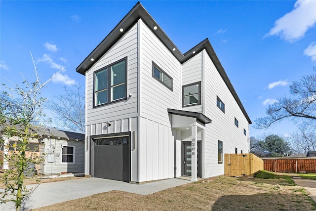 view of front facade featuring a garage, driveway, board and batten siding, and fence