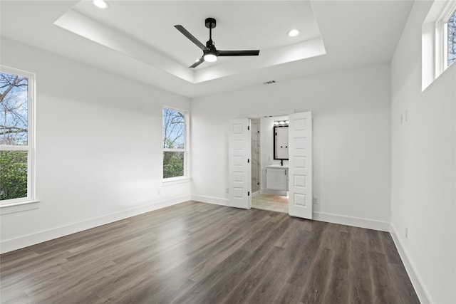 unfurnished bedroom with dark wood-style floors, recessed lighting, a raised ceiling, visible vents, and baseboards