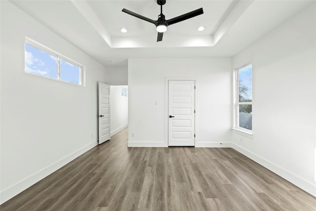 unfurnished bedroom featuring a raised ceiling, baseboards, and wood finished floors