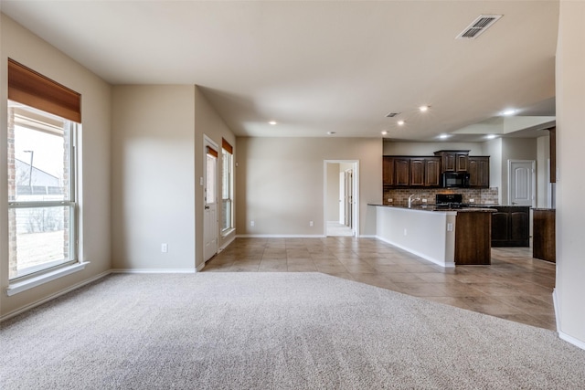 kitchen featuring dark countertops, light colored carpet, visible vents, dark brown cabinetry, and black microwave