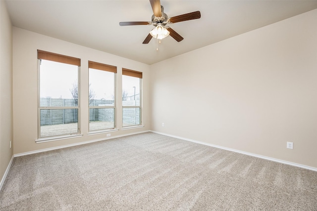 carpeted empty room featuring a ceiling fan and baseboards