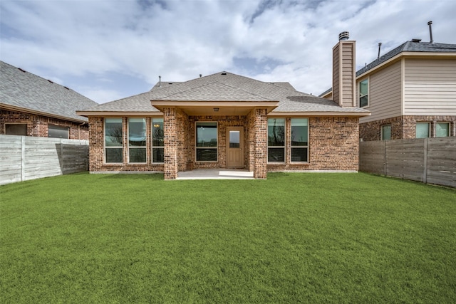 back of property featuring roof with shingles, a lawn, and a fenced backyard