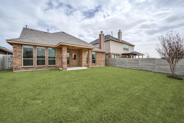 back of house with a patio area, a fenced backyard, a shingled roof, and a lawn