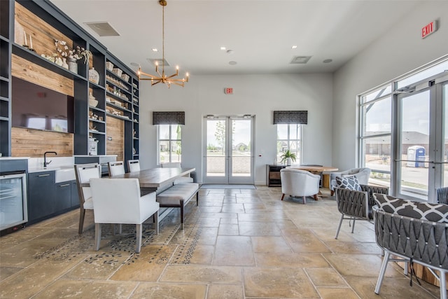 dining space featuring visible vents, wine cooler, an inviting chandelier, stone tile flooring, and french doors