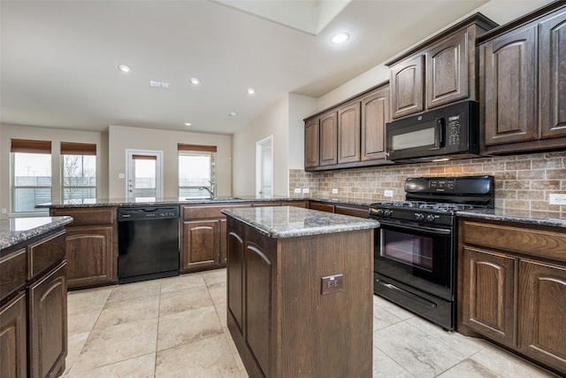 kitchen with dark stone counters, a sink, and black appliances