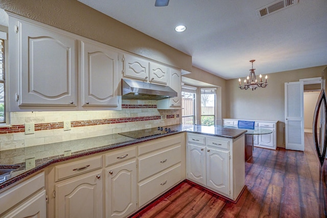 kitchen with visible vents, under cabinet range hood, a peninsula, black electric cooktop, and dark wood-style flooring