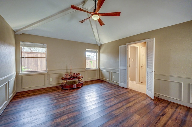 empty room with lofted ceiling with beams, wood-type flooring, wainscoting, and a ceiling fan