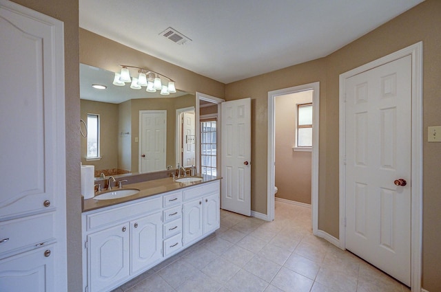 full bathroom with visible vents, a healthy amount of sunlight, and a sink