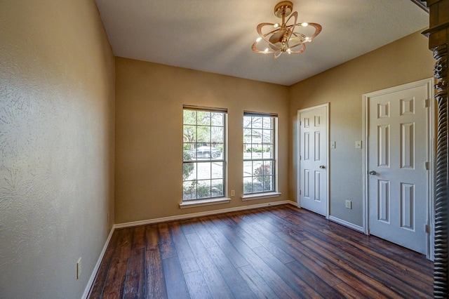 entryway featuring an inviting chandelier, dark wood-type flooring, a textured wall, and baseboards