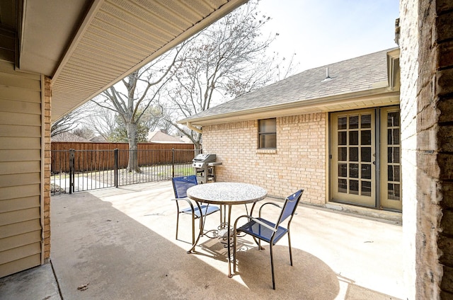 view of patio with fence and a grill