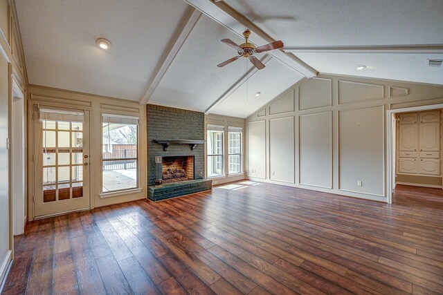 unfurnished living room with a decorative wall, plenty of natural light, a fireplace, and lofted ceiling with beams