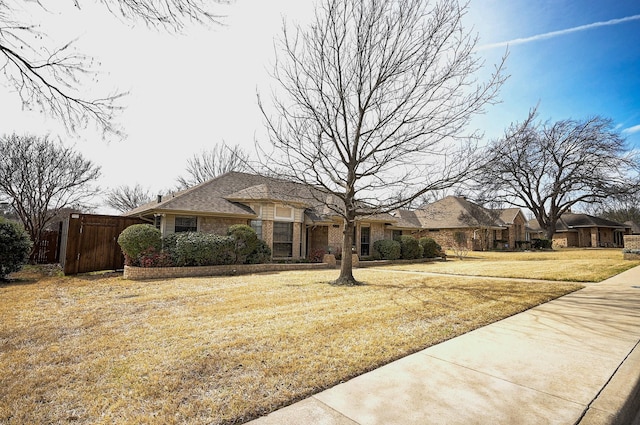 french country inspired facade featuring brick siding, a front lawn, and fence