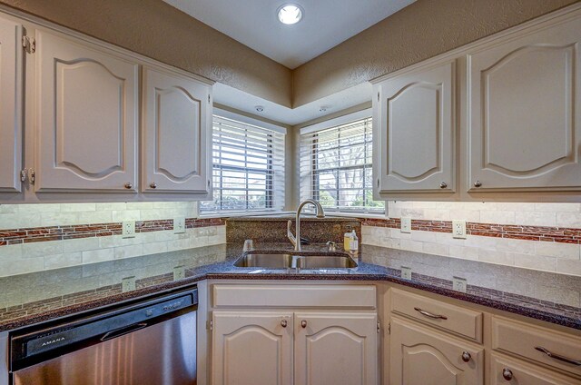 kitchen with a sink, backsplash, a textured wall, and stainless steel dishwasher