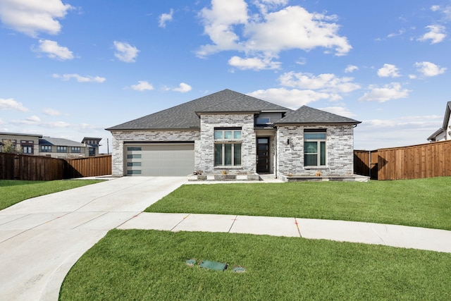 prairie-style home featuring roof with shingles, a front yard, fence, a garage, and driveway