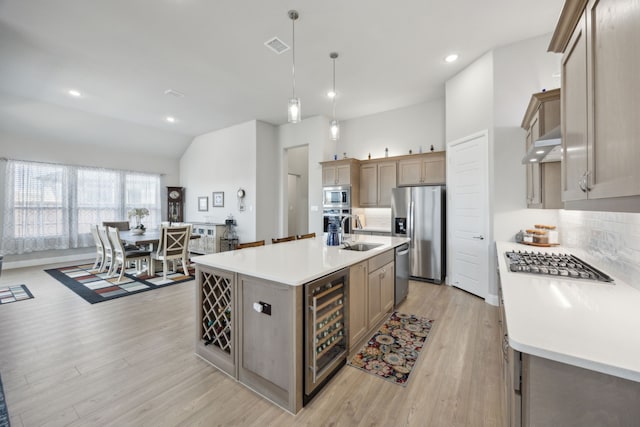 kitchen featuring light countertops, appliances with stainless steel finishes, light wood-style floors, a sink, and beverage cooler