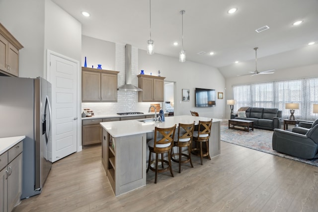 kitchen featuring visible vents, wall chimney exhaust hood, open floor plan, stainless steel appliances, and light countertops