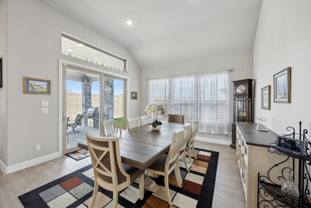 dining space featuring light wood finished floors, baseboards, vaulted ceiling, and a wealth of natural light