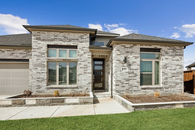 view of front of home featuring a shingled roof and brick siding