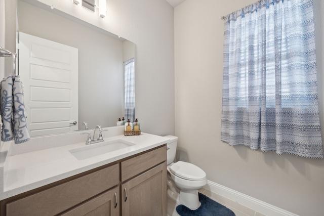 bathroom with vanity, toilet, and baseboards