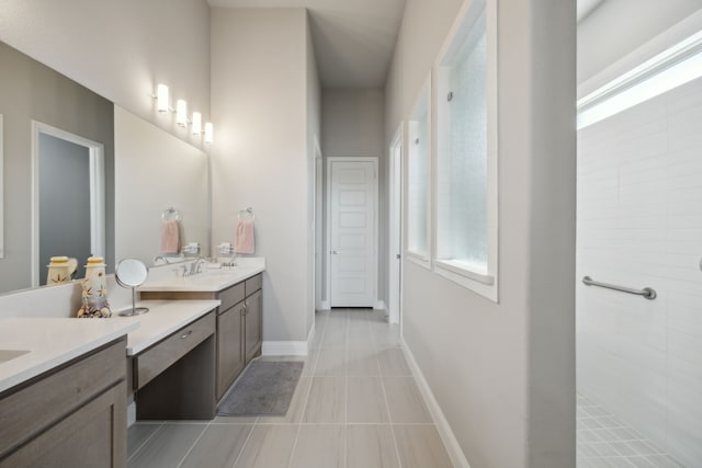 full bathroom with tile patterned floors, baseboards, tiled shower, and vanity