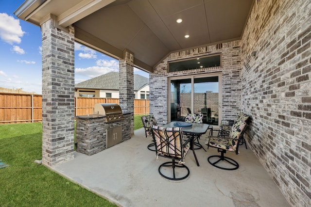 view of patio / terrace featuring outdoor dining space, fence, grilling area, and an outdoor kitchen