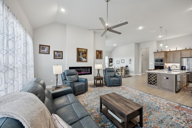 living area featuring baseboards, vaulted ceiling, light wood finished floors, and ceiling fan