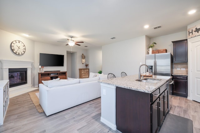 kitchen with stainless steel refrigerator with ice dispenser, visible vents, light wood-style flooring, backsplash, and a sink