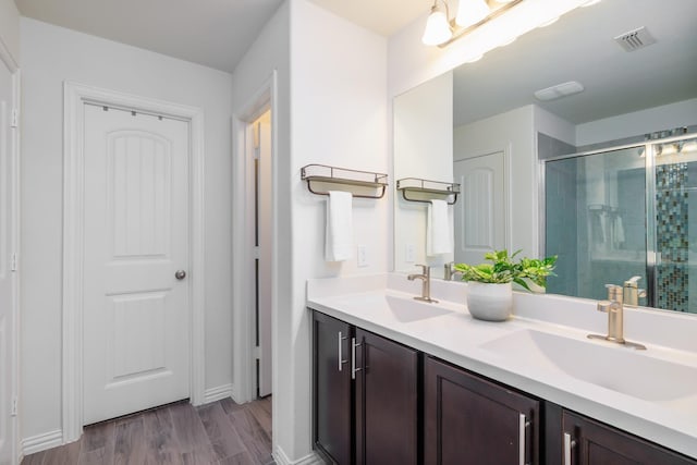 bathroom with a stall shower, visible vents, a sink, and wood finished floors