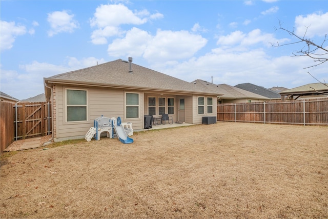 rear view of property featuring a fenced backyard, a shingled roof, cooling unit, and a patio