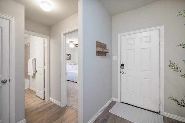 foyer entrance with a ceiling fan, baseboards, and wood finished floors