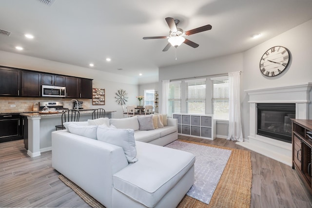 living room featuring light wood-type flooring, visible vents, and recessed lighting