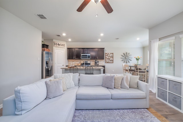 living room featuring a ceiling fan, recessed lighting, visible vents, and wood finished floors