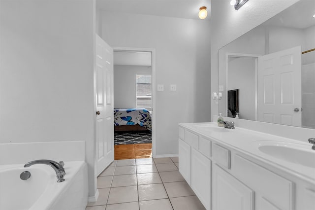 bathroom featuring a tub, tile patterned flooring, a sink, and ensuite bathroom