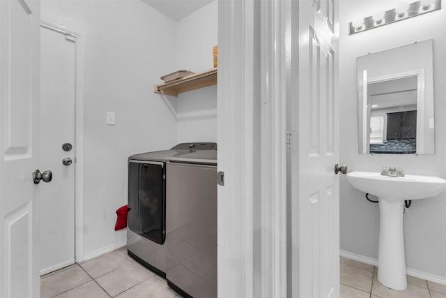 washroom with washing machine and clothes dryer, light tile patterned floors, a sink, laundry area, and baseboards