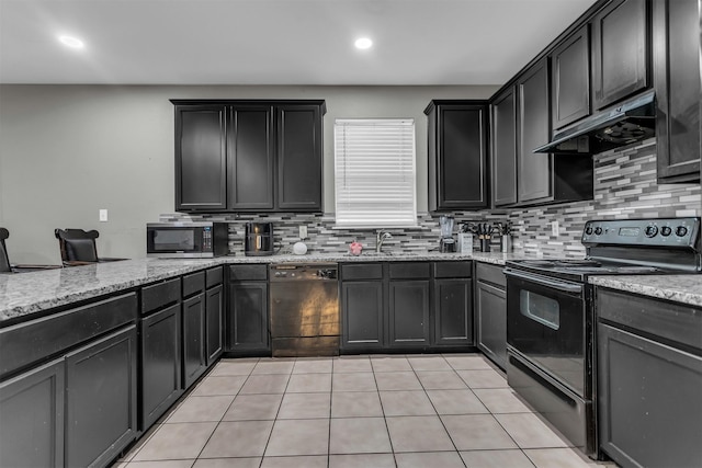 kitchen with black appliances, tasteful backsplash, under cabinet range hood, and light stone counters