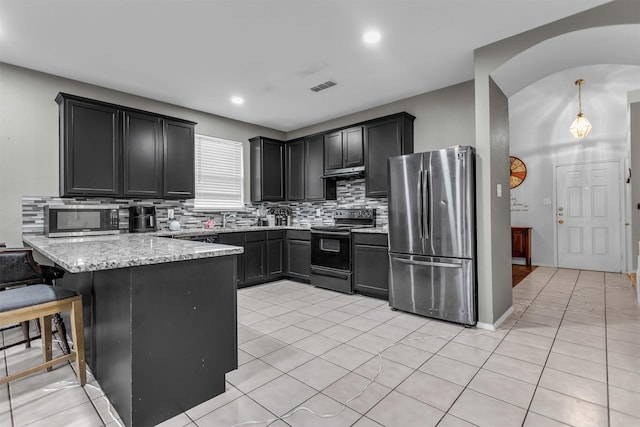 kitchen featuring visible vents, backsplash, appliances with stainless steel finishes, light stone countertops, and a peninsula