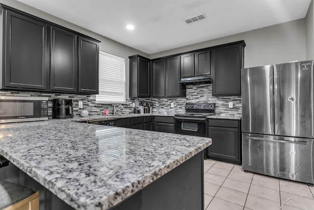 kitchen with light tile patterned floors, stainless steel appliances, visible vents, a peninsula, and under cabinet range hood