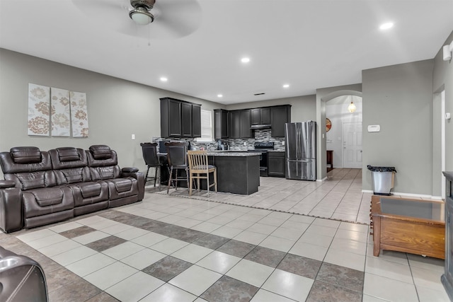 living room featuring arched walkways, light tile patterned flooring, a ceiling fan, and recessed lighting