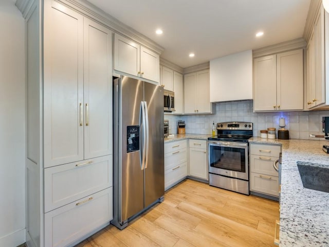 kitchen with decorative backsplash, appliances with stainless steel finishes, light stone counters, light wood-style floors, and recessed lighting