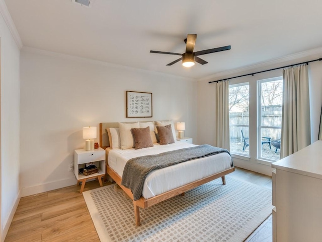 bedroom featuring light wood-type flooring, a ceiling fan, baseboards, and crown molding